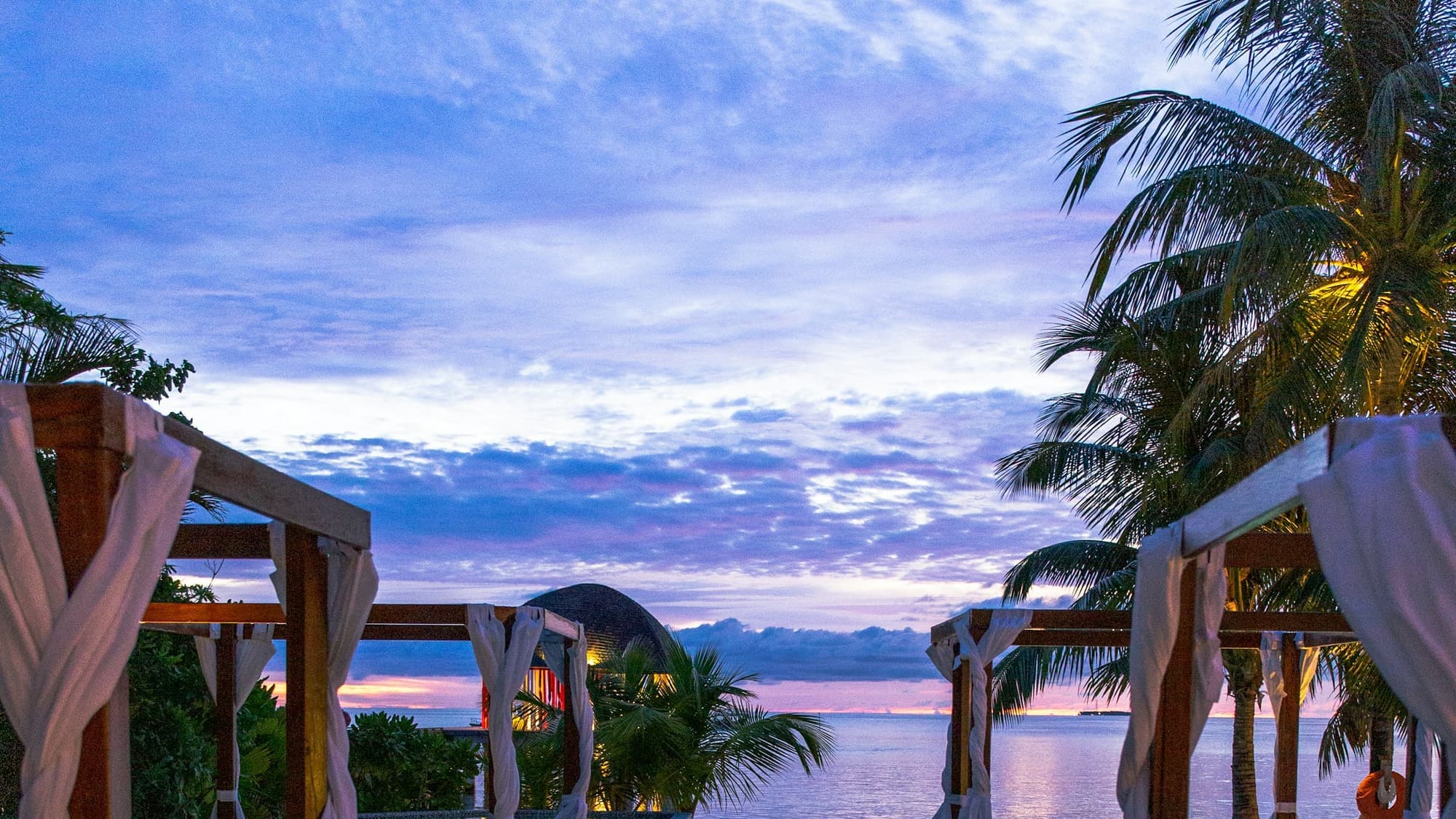 Negril coastline at golden hour from a villa terrace — sea and palms beyond, warm human light in the foreground