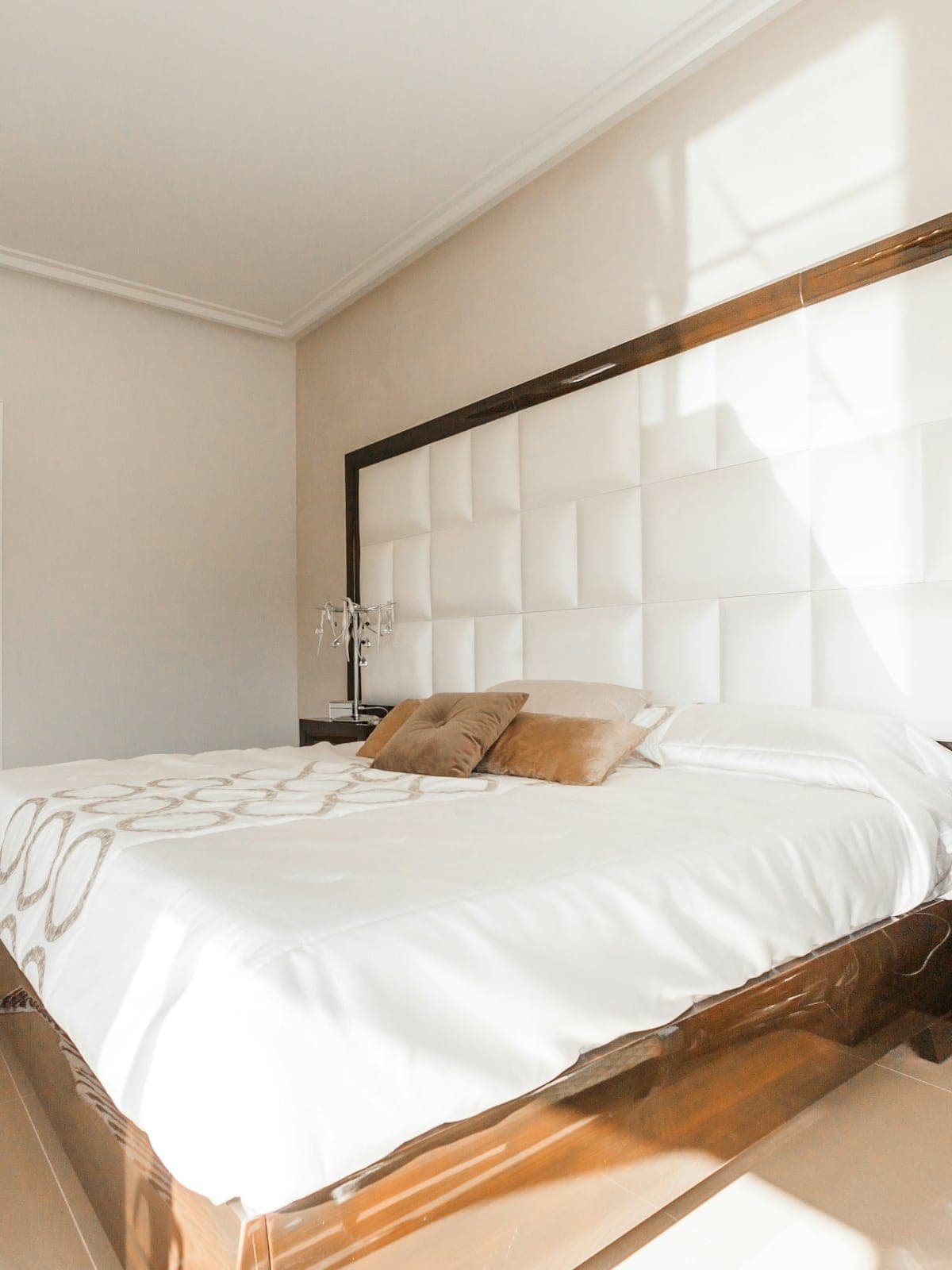 Fresh white linen being smoothed in a sea-lit bedroom